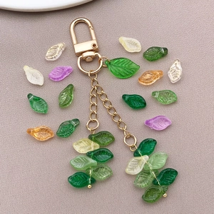 Detailed close-up of mini glass leaf beads with gold lobster clasp for DIY jewelry