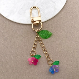 Detail of gradient glass cherry blossom charms on a gold keychain for DIY hair accessories