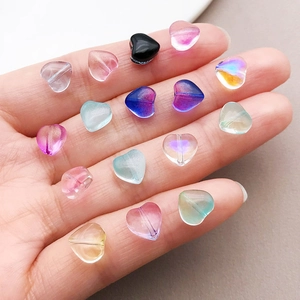 Gros plan de perles en verre de 8mm en forme de cœur avec dégradé coloré sur une main