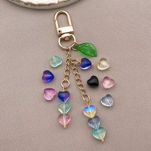 Détail de perles de cœur givrées colorées sur un porte-clés doré avec un pendentif feuille