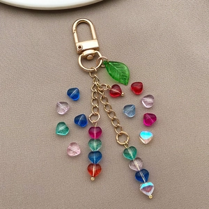 Detail of colorful 6mm glass heart beads and leaf pendant on a golden keychain
