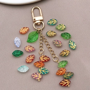 Dettaglio di perle a foglia in vetro 11x7mm bordate d'oro su tessuto grigio