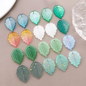 Flat lay of colorful leaf-shaped glass charms with gold glitter for DIY jewelry making