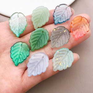 Macro detail of mixed color glass leaf pendants with gold foil for DIY jewelry making