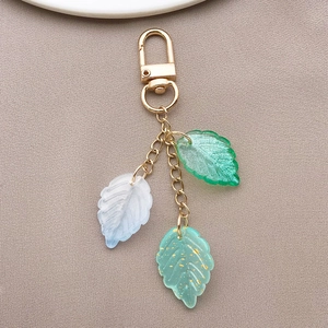 Macro detail of mixed color glass leaf pendants with gold foil accents and metal clasp