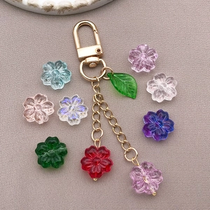 Close-up of translucent cherry blossom glass beads and gold metal leaf keychain charms