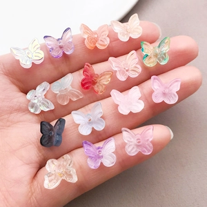 Hand holding colorful 10mm butterfly glass beads showing size and 3D crystal texture