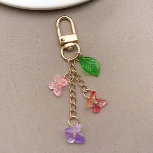 Macro view of colorful butterfly and green leaf charms on a golden metal keychain