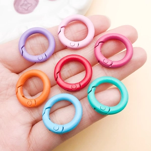 Close-up of hand holding colorful matte 20mm round spring gate rings for DIY accessories