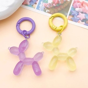 Macro shot of purple and yellow glitter resin balloon dog keychains with matte plastic rings