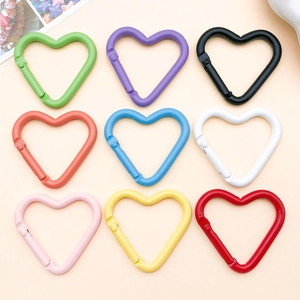 Dettaglio di 9 moschettoni a cuore in lega di alluminio colorati disposti in griglia