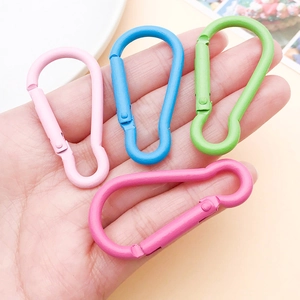 Close-up of four matte colorful aluminum carabiners held in hand for size display