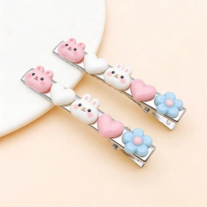 Détail de pinces à cheveux en fer avec des breloques lapin et fleur en résine pastel