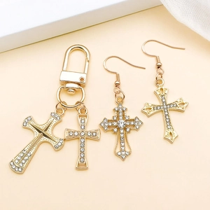 Detailed macro of gold-plated alloy cross pendant and earrings with clear rhinestones