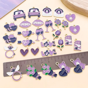 Detalle de dijes de aleación de esmalte morado con base dorada y regla para dimensiones