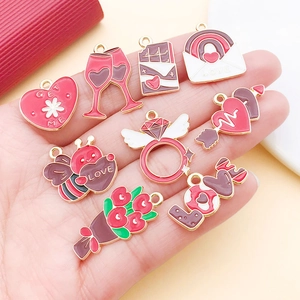Detailed view of red Valentine enamel alloy charms held in hand for size comparison