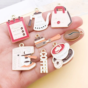 Detailed view of coffee-themed alloy charms being held by hand for scale and texture