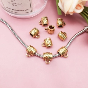 Detail of floral engraved gold pendant charm on a silver snake chain bracelet