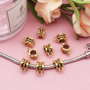 Detail of vintage gold bow-textured charms with hanging loops for DIY jewelry making