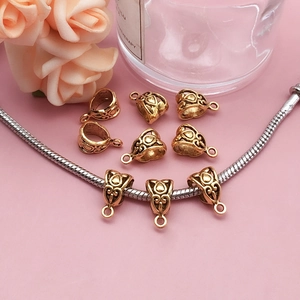 Detail of antique gold pendant connector with hollow heart patterns on a snake chain