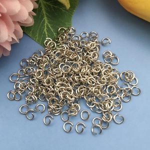 Detailansicht silberner Biegeringe für DIY-Schmuckherstellung auf floralem Hintergrund