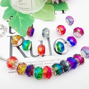 Macro detail of colorful gradient faceted charm beads on a silver snake chain bracelet
