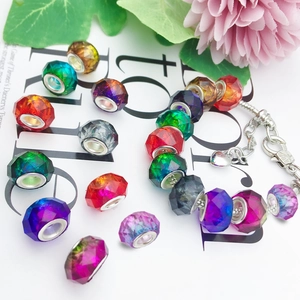 Macro shot of colorful faceted gradient beads and silver charm bracelet on magazine
