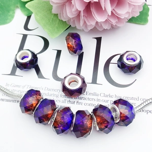 Macro detail of faceted gradient glass charms on a silver snake chain bracelet