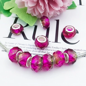 Macro view of faceted magenta beads with silver cores on a metal snake chain bracelet