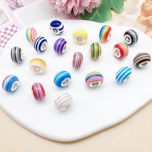 Macro shot of colorful striped resin beads with metal cores on a white heart tray