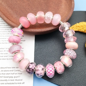 Detalle de cuentas con motivos florales rosas y colgantes facetados para pulseras DIY