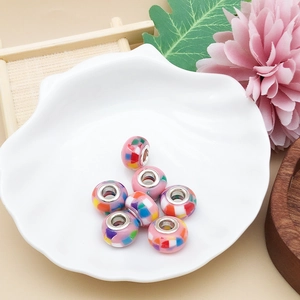 Makroaufnahme bunter Acrylperlen im Pandora-Stil mit Metalleinsatz in Muschelschale