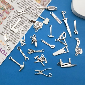 Macro shot of assorted silver alloy tool pendants like saws and hammers for DIY jewelry