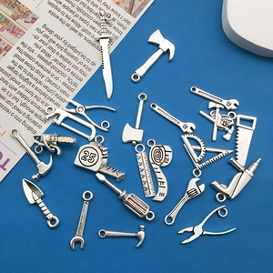 Detailed macro view of 20 assorted vintage silver alloy tool charms on a blue background