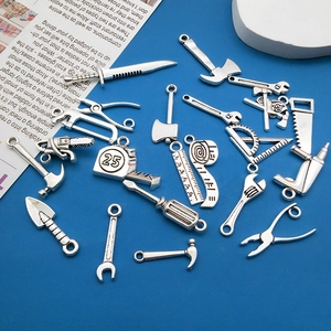 Macro shot of antique silver DIY tool charms like hammer, saw, and ruler on blue background