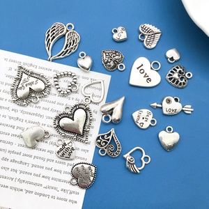 Macro detail of assorted vintage silver heart charms with engraved love motifs and wings