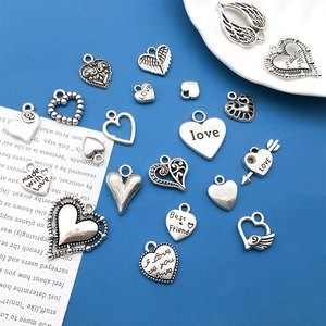 Macro view of vintage heart charms and angel wings with engraved text for DIY jewelry