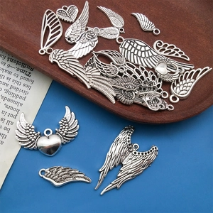 Vue détaillée de breloques plumes et ailes d'ange en alliage argenté vintage avec texture relief