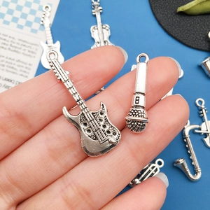 Macro detail of various antique silver musical instrument pendants held in hand