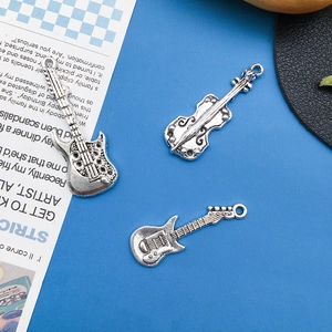 Detailed flat lay of antique silver guitar and violin pendants on blue background