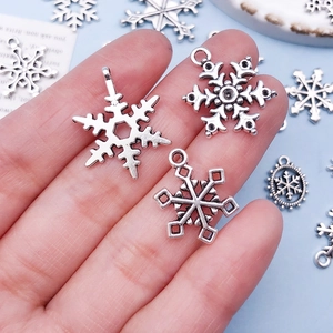 Makroaufnahme von silbernen Schneeflocken-Anhängern für DIY-Schmuck in der Hand