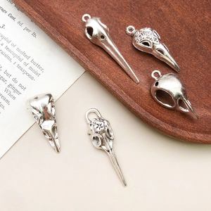 Detailed macro view of five vintage silver bird skull alloy charms on antique book pages