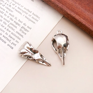 Macro shot of two vintage silver bird skull charms with realistic bone details and eye sockets