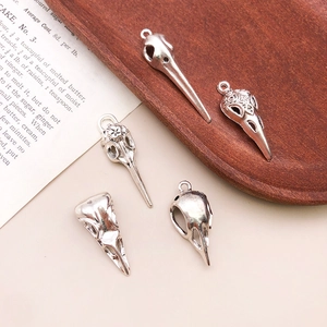Detailed macro view of vintage silver bird skull charms with intricate antique carvings