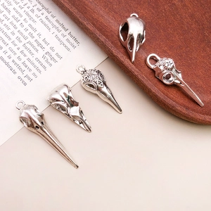 Macro shot of vintage silver bird skull pendants with gothic carvings on aged book pages