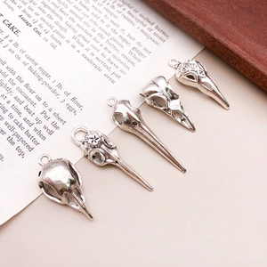 Detailed view of five vintage silver bird skull alloy charms on a retro book background
