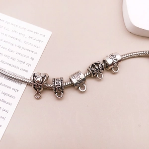 Detalle de pulsera de dijes de plata vintage con grabado LOVE y motivos florales