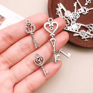 Hand holding vintage silver alloy heart key pendants for DIY necklaces and crafts