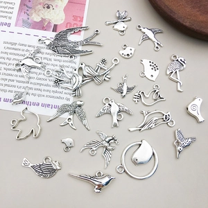 Detalle macro de varios colgantes de pájaros plateados vintage para hacer joyas DIY