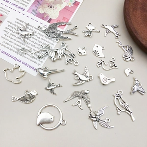 Detalle macro de varios colgantes de pájaros en plata antigua para creación de joyas DIY